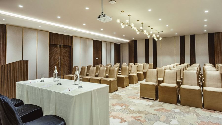 A hall at Mango Hill Central, Chennai, with chairs in a theatre-style setup and a table with two chairs at the front of the room.