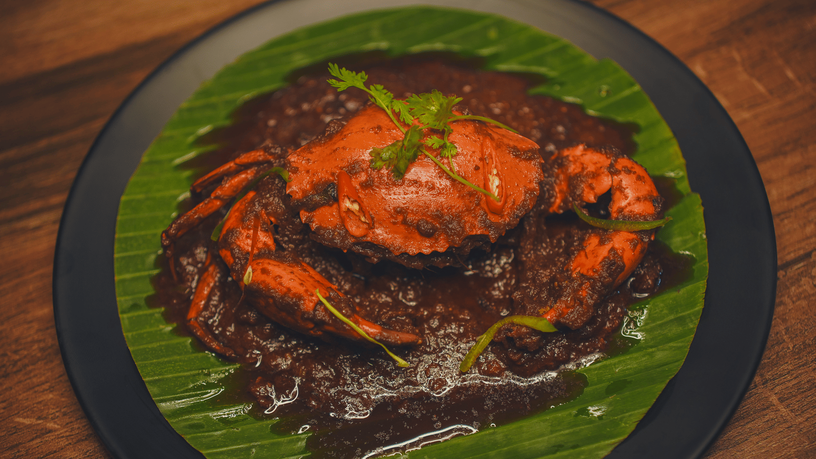 A dish plated on a banana leaf featuring whole crab smeared with spices at Dip Holidays.