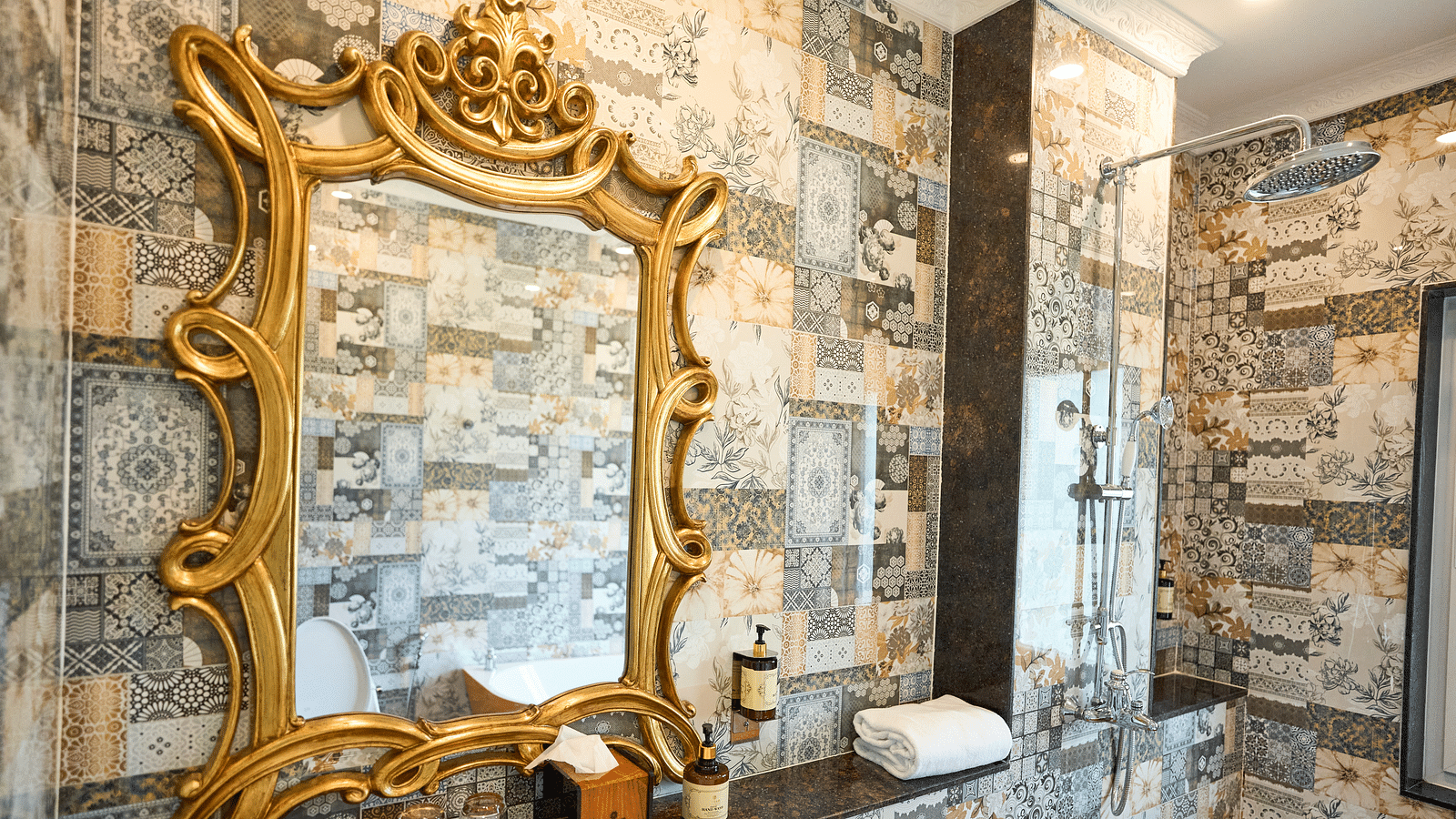 A mirror with decorative framing and essentials arranged below it at Mayfair Manor, Alibag