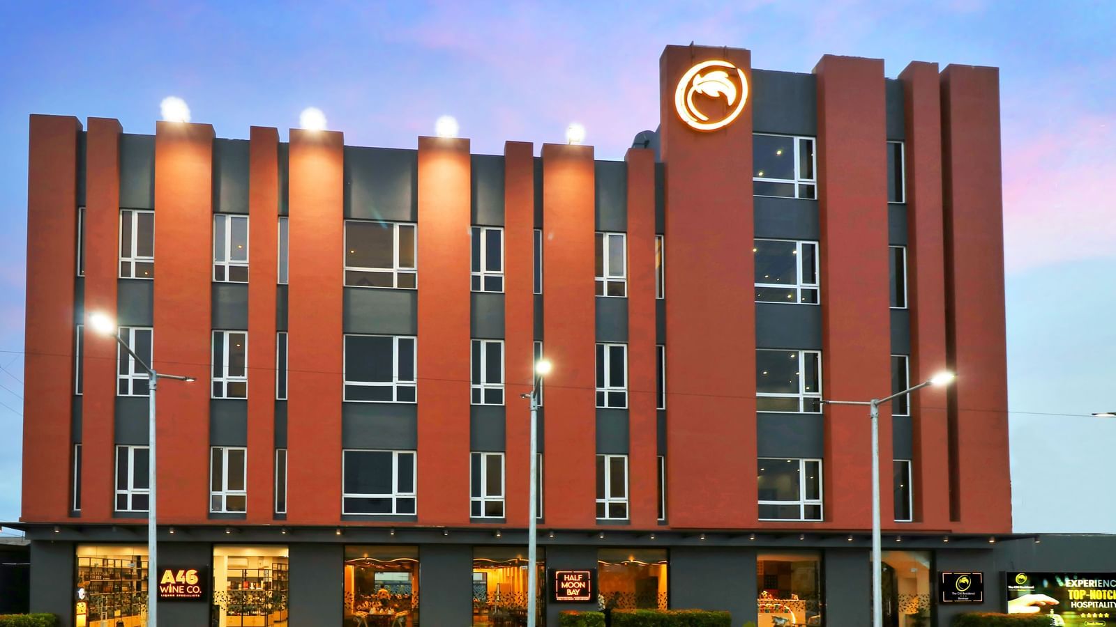 A hotel building with orange and grey facade illuminated at dusk | The Citi Residenci Hotel Banskopa