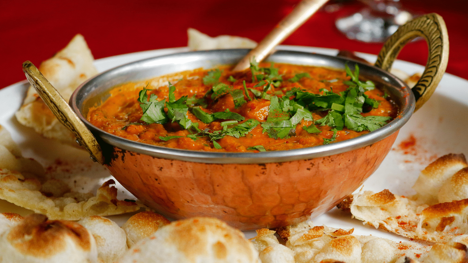 image of an indian preparation of paneer topped with chopped coriander leaves served with naan