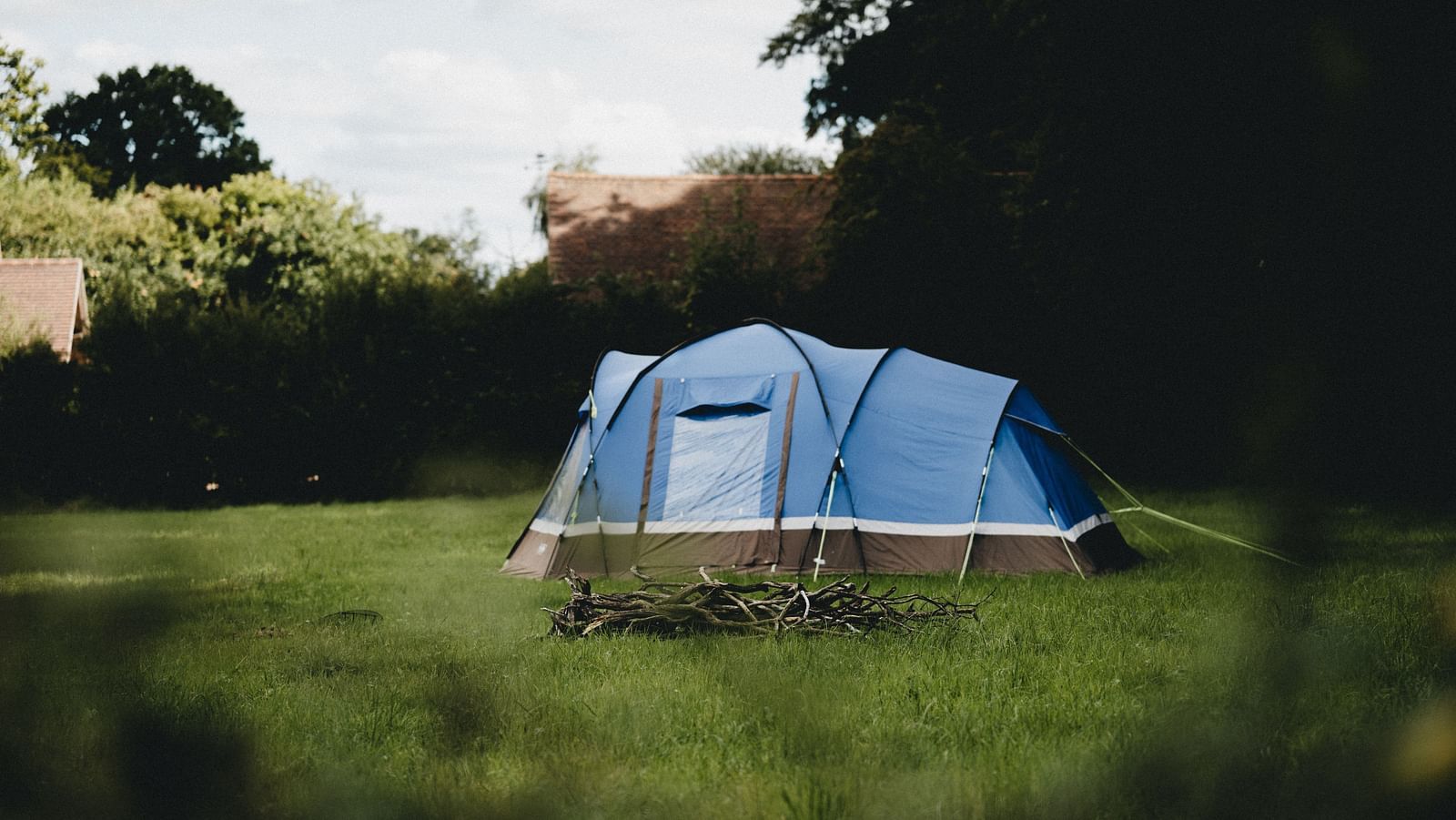 an image of a blue tent amidst a garden with morning sky in the background