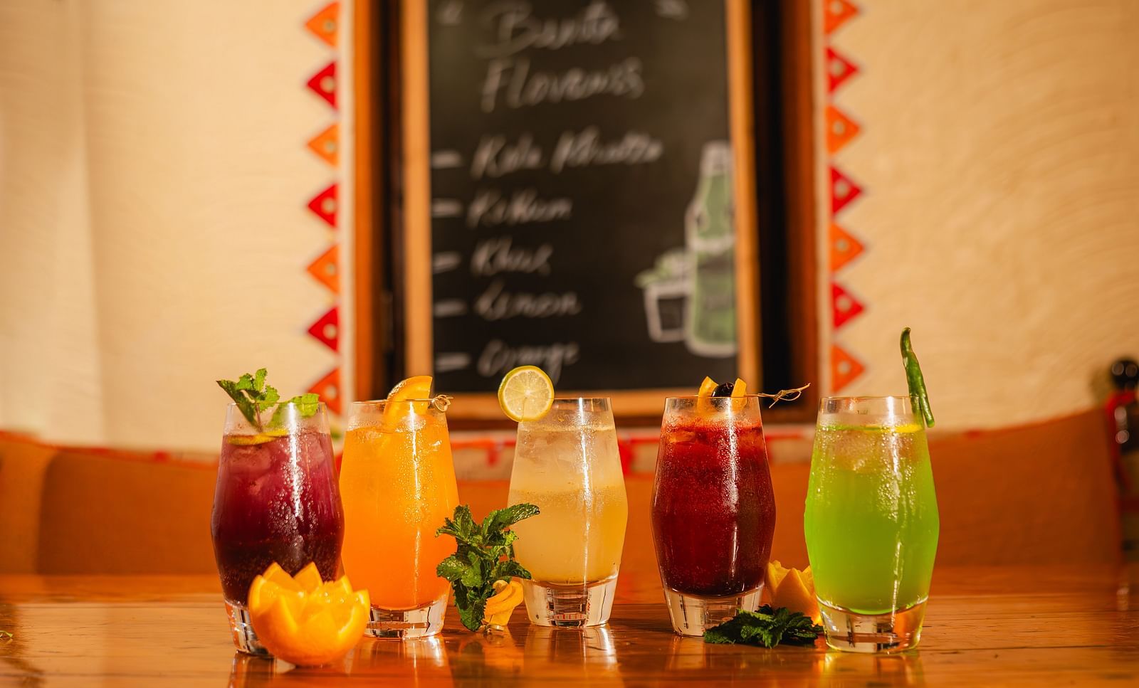 Assorted flavoured mocktails served in glasses placed on a table with a menu board displayed in the background
