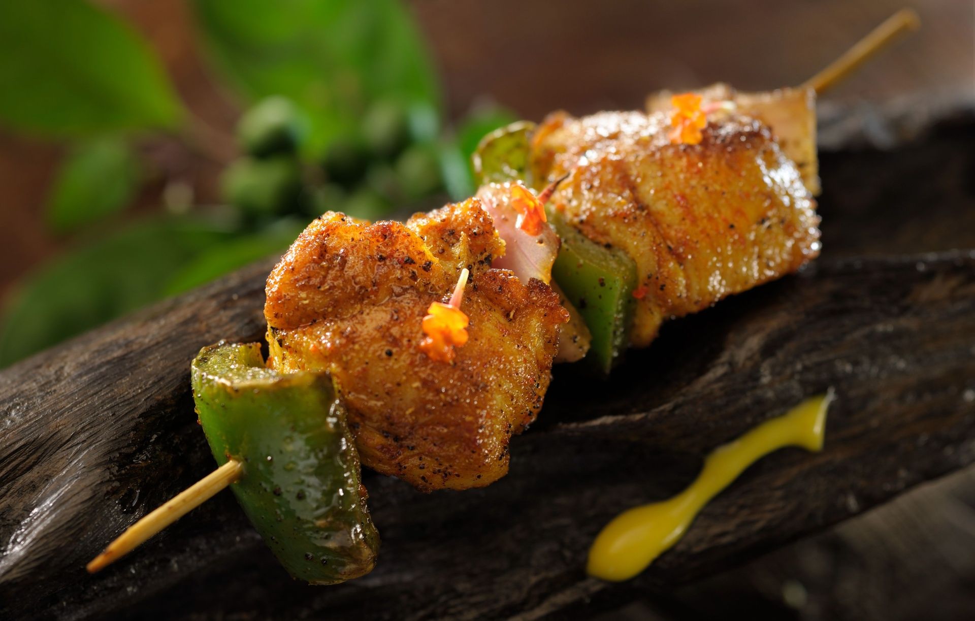 Grilled chicken and bell pepper skewers on wood.