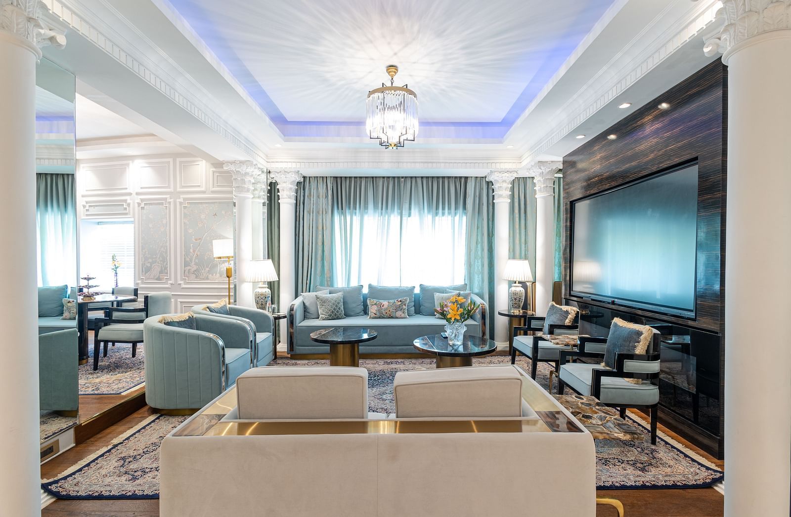 Claridges Suite at The Claridges New Delhi, featuring a cosy sofa beneath a chandelier and surrounded by elegant ambient lighting