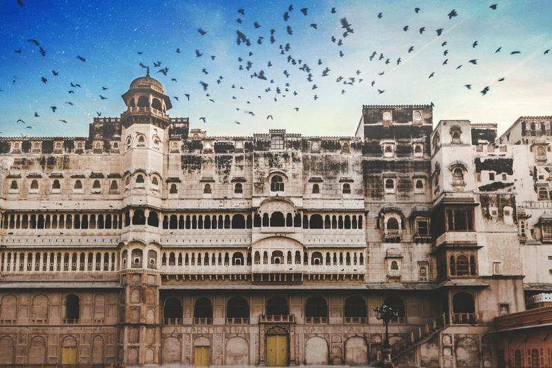 Sandstone Rajasthani palace facade with birds in flight at dusk