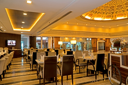 Elegant restaurant dining area with neatly arranged tables, warm ambient lighting and a refined setting for comfortable all-day dining.