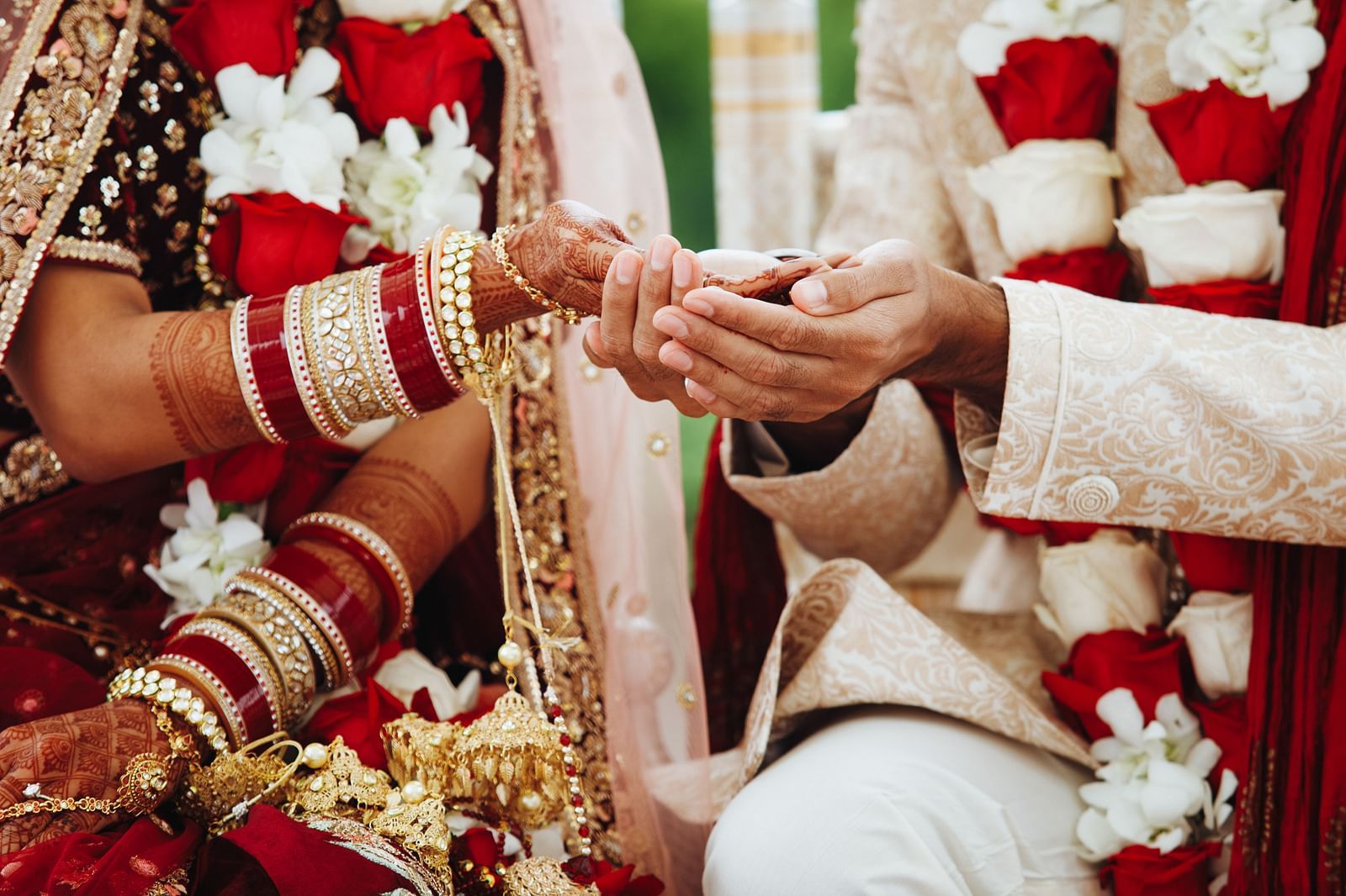 Close-up view of the bride and groom holding hands, both in wedding attire.