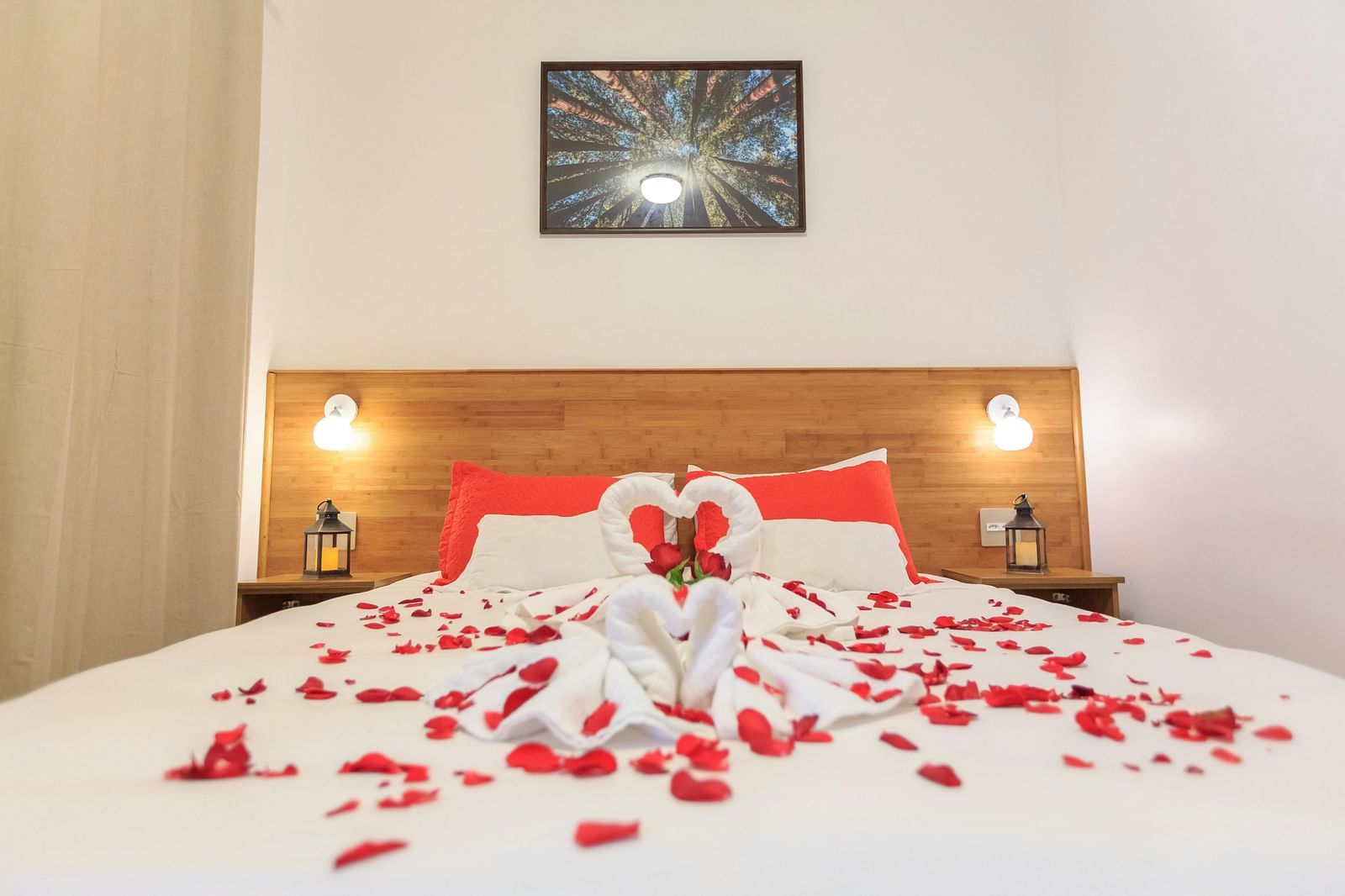 A bed decorated with flower petals and towels folded in the shape of a swan.