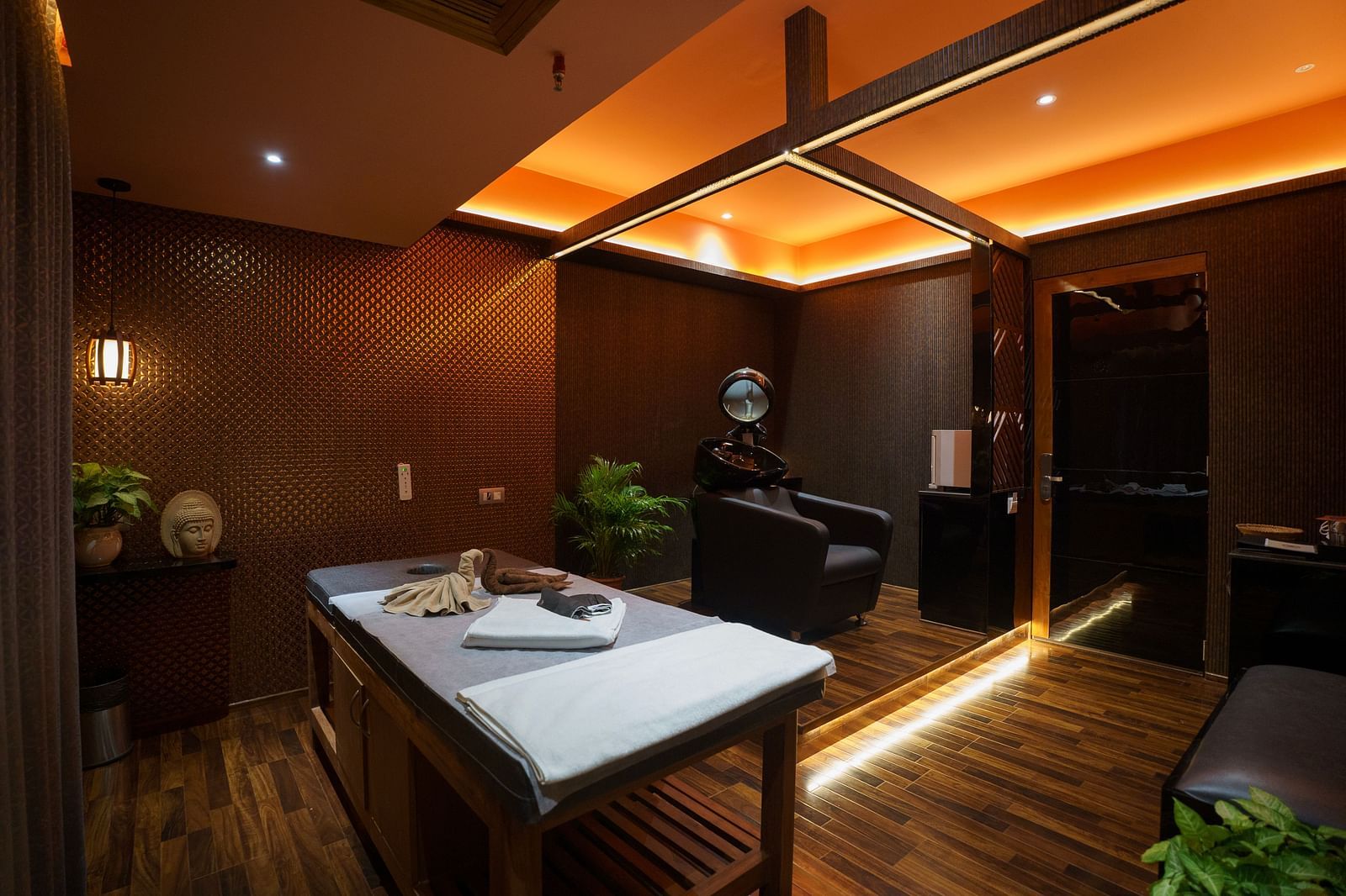 A luxurious spa room with a wooden massage table and a relaxing armchair - Coral Reef Hotel & Spa, Port Blair