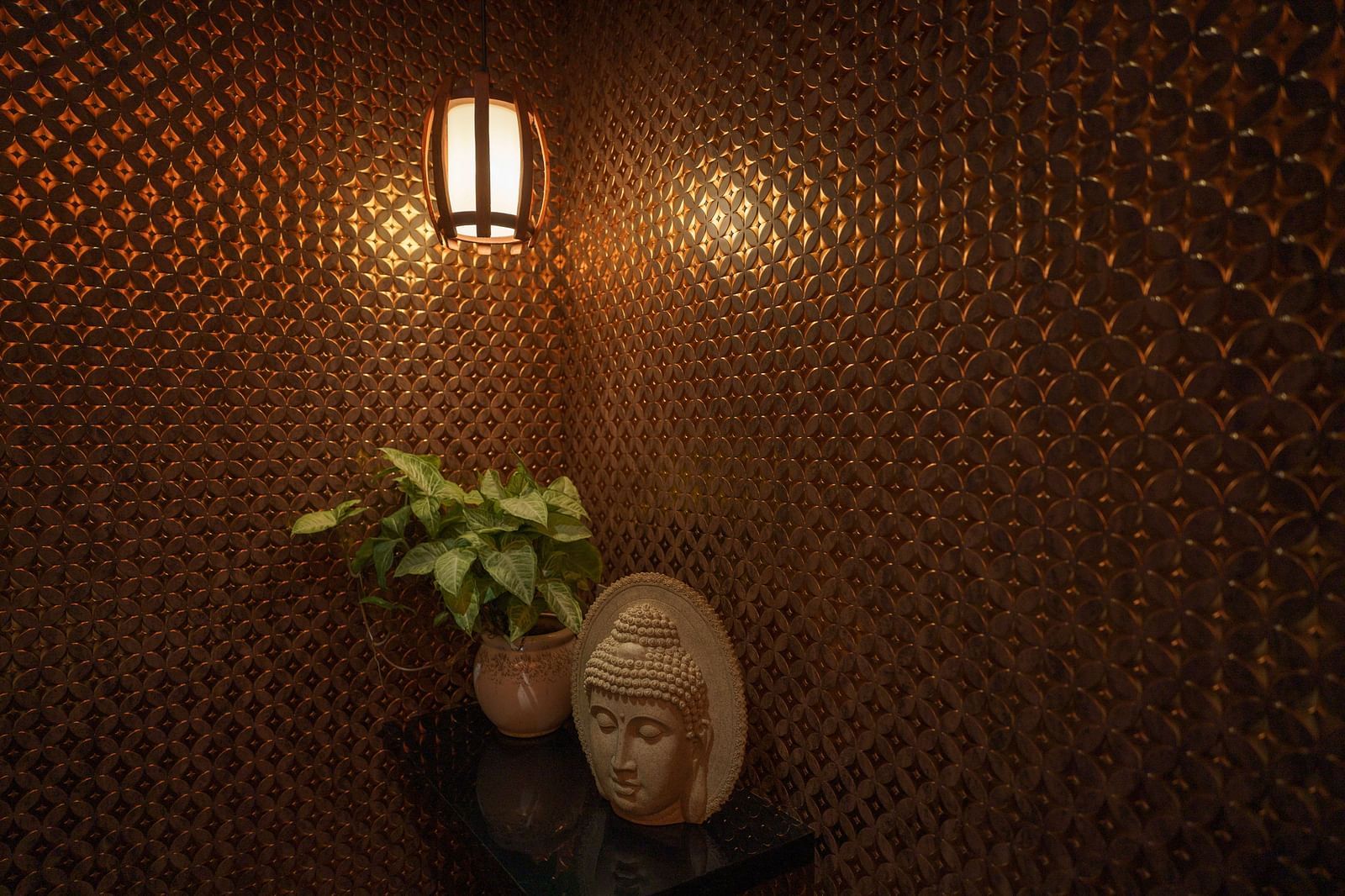Image of an aesthetic corner of the spa at Coral Reef Hotel & Spa in Port Blair featuring a warm lit lamp below which a plant and a showpiece of Buddha is placed