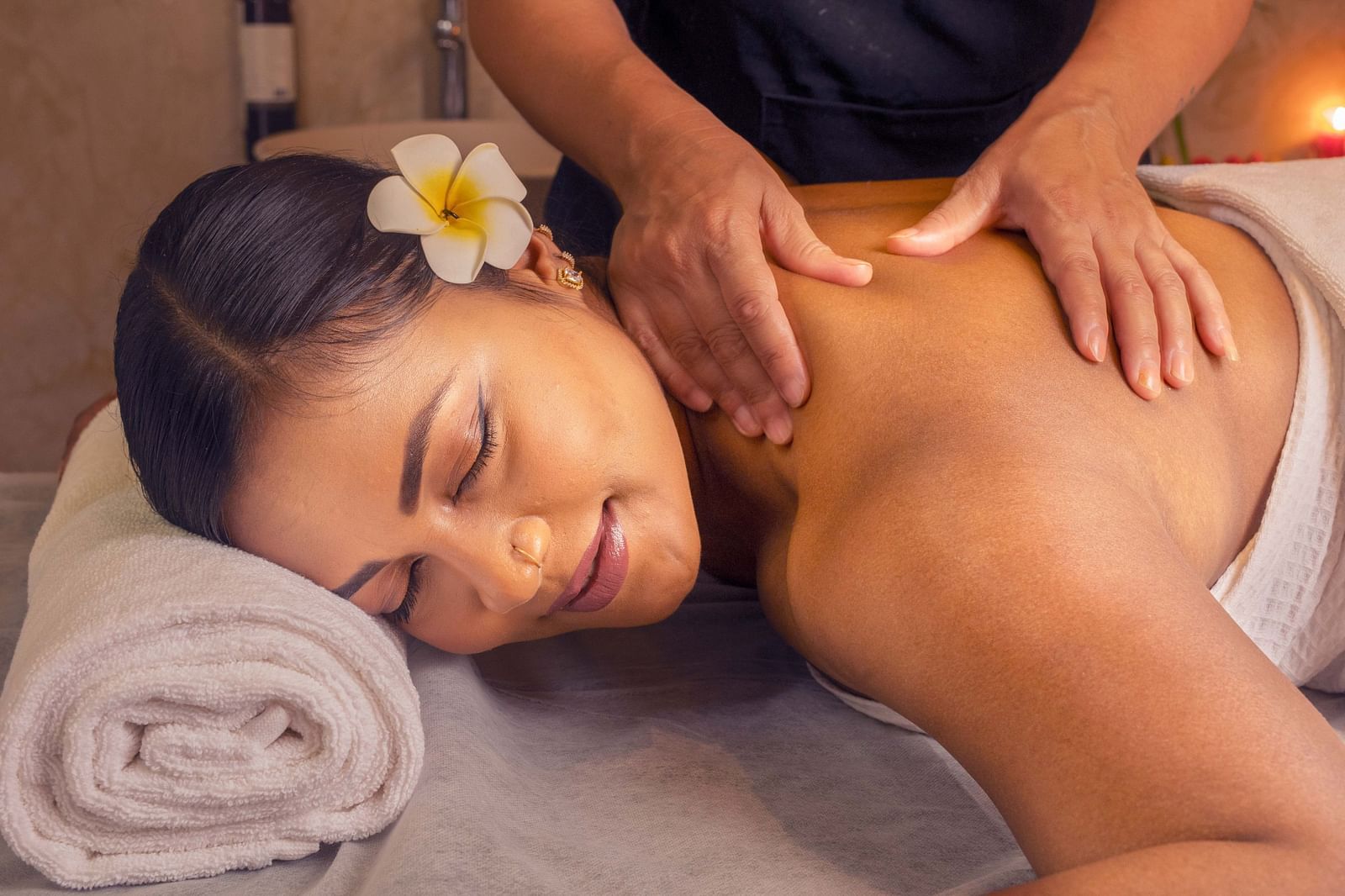 A woman receiving a soothing massage, surrounded by soft lighting and fresh flowers. The calm setting helps create a peaceful, spa-like experience - Coral Reef Resort & Spa, Havelock