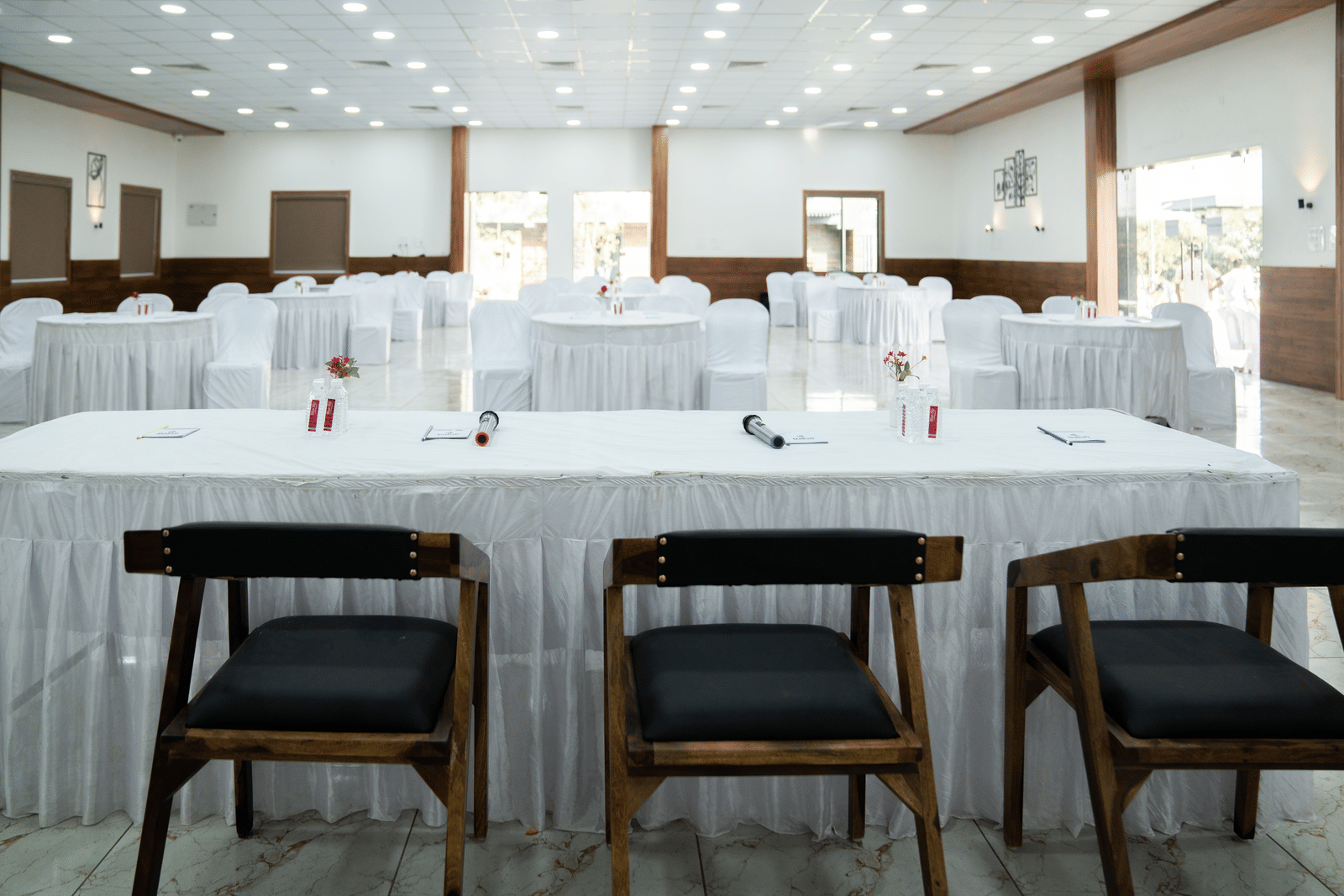 A neatly set-up banquet hall of Daksh Eden Greenz, furnished with chairs facing a table for the central panel.