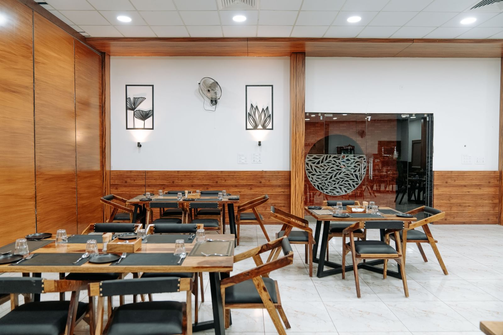 A shot of some tables at the restaurant of the resort that has wooden furnishing and wall mounted paintings.