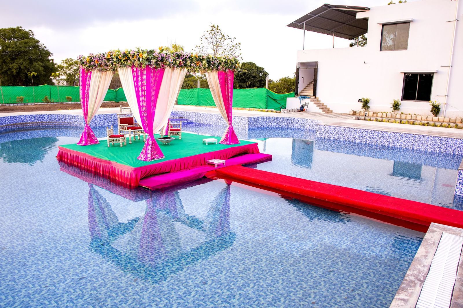 Poolside wedding mandap setup at Daksh Hotels and Resorts, with floating stage decor in vibrant pink.