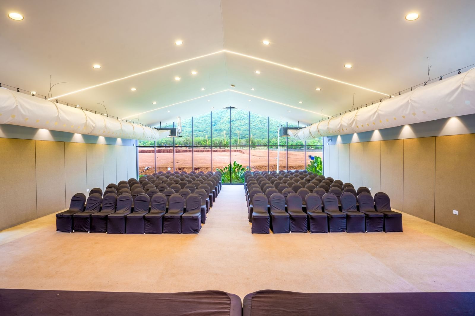 Brightly lit Love Letter at Darza Resort arranged with rows of dark chairs facing a stage area