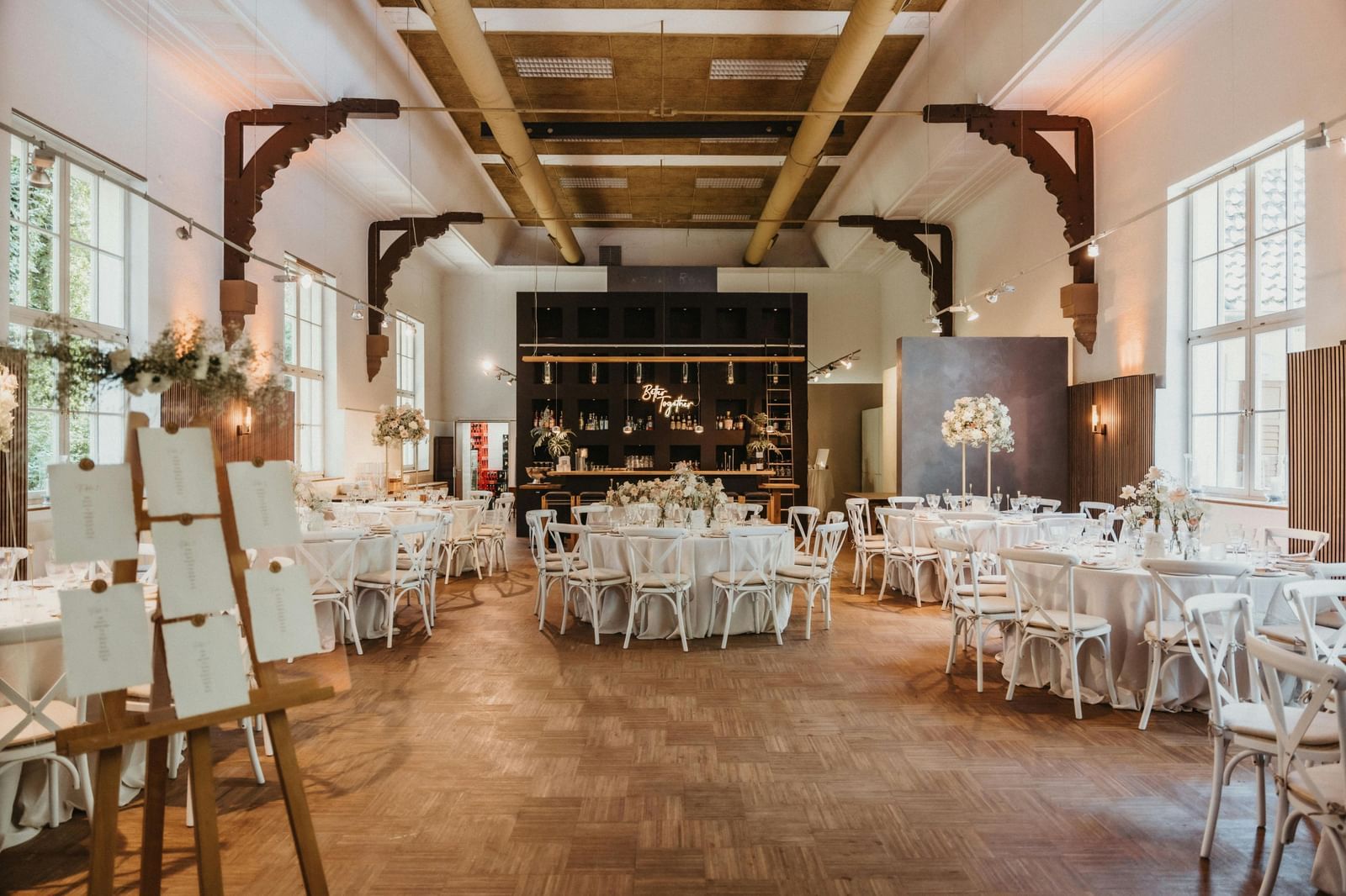 image of a banquet hall with well arranged tables and chairs decorated with flowers and cutlery 