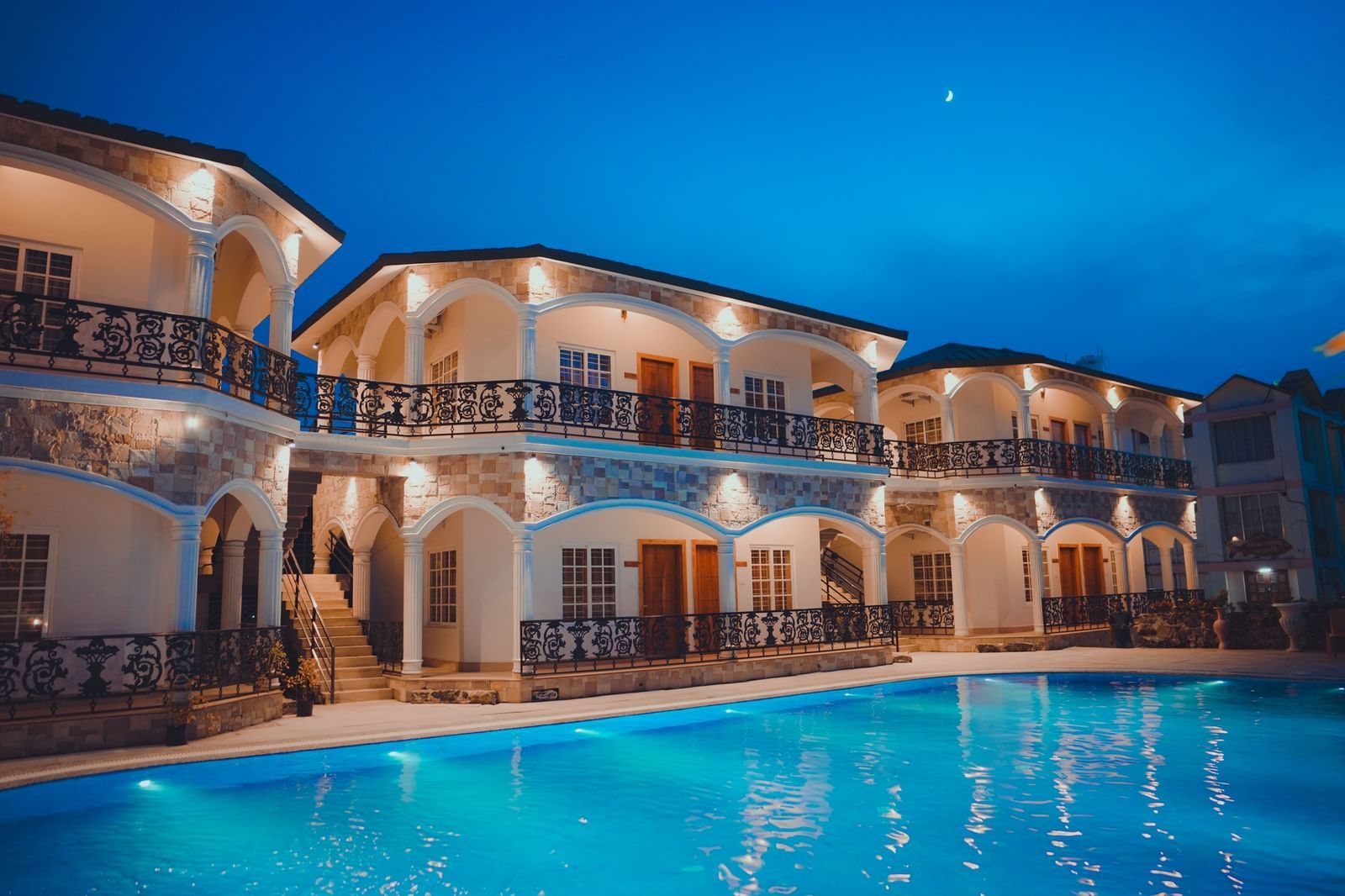 facade image of our hotel in birbhum in the late evening with a beautiful view of the swimming pool in the foreground
