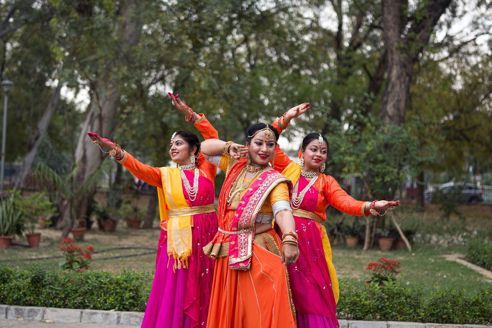 image of three women engaged in an Indian classical dance form with a lush green background in the surroundings