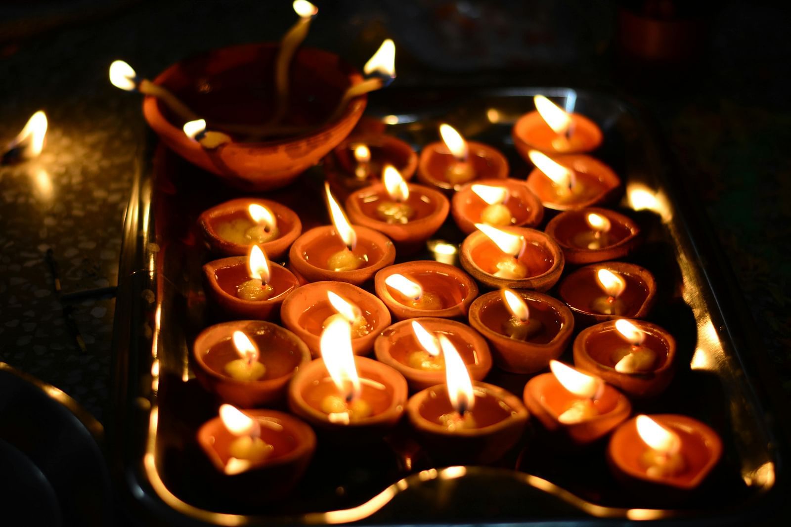 image of several earthen oil lamps lit up in a dark space