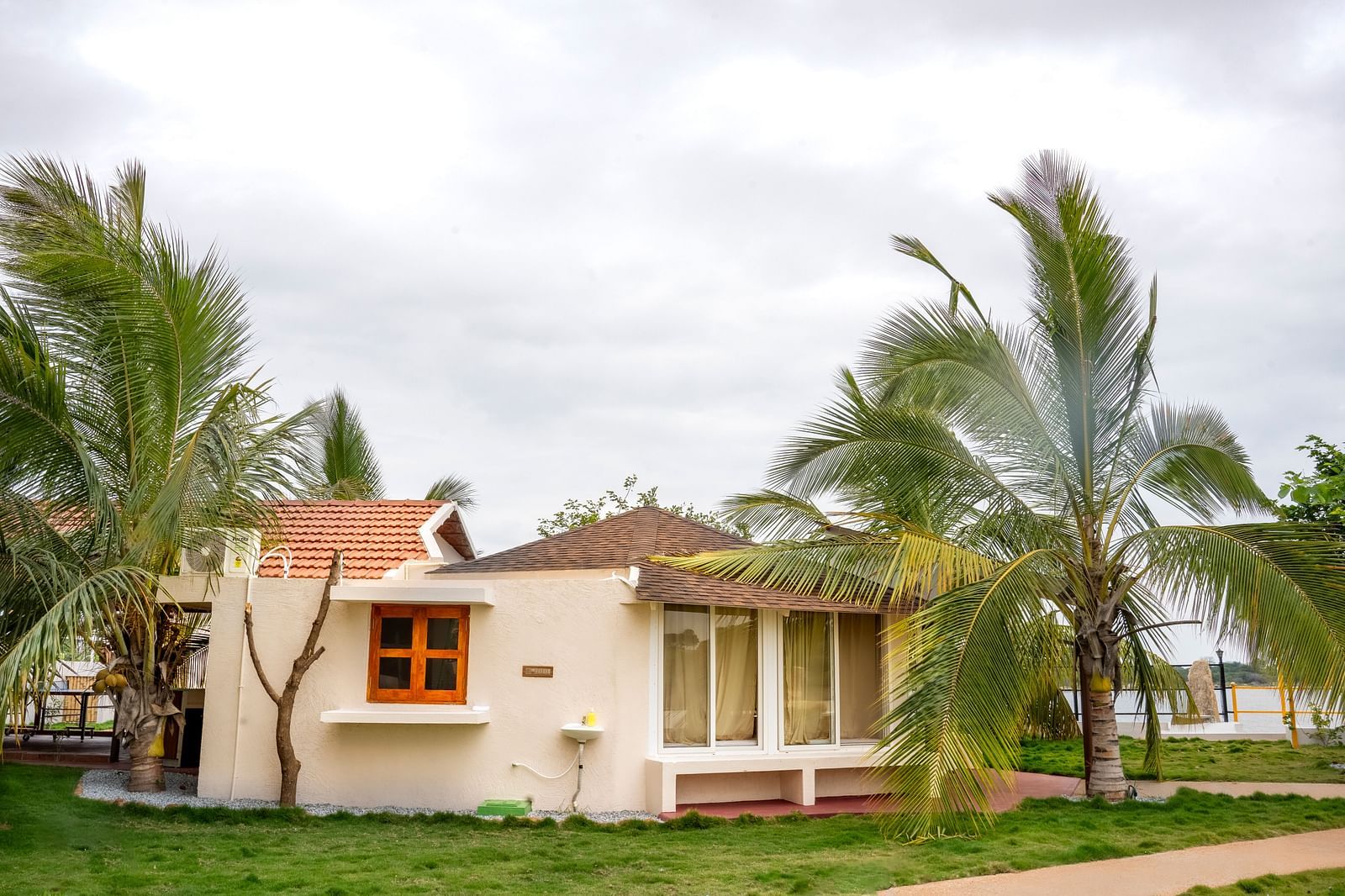 Image of a villa amidst a lawn and palm trees