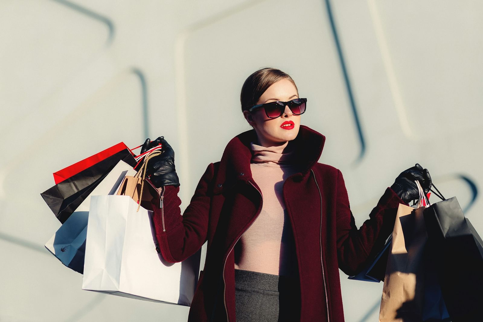 A close up shot of a woman holding many shopping bags in both hands and posing for a picture.