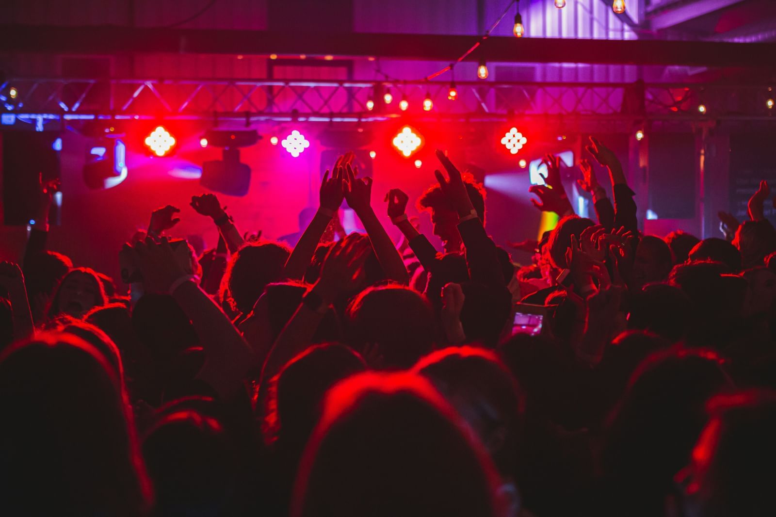 A view from inside the club of people dancing and neon lights on them - Jamaica Clubs Nightlife