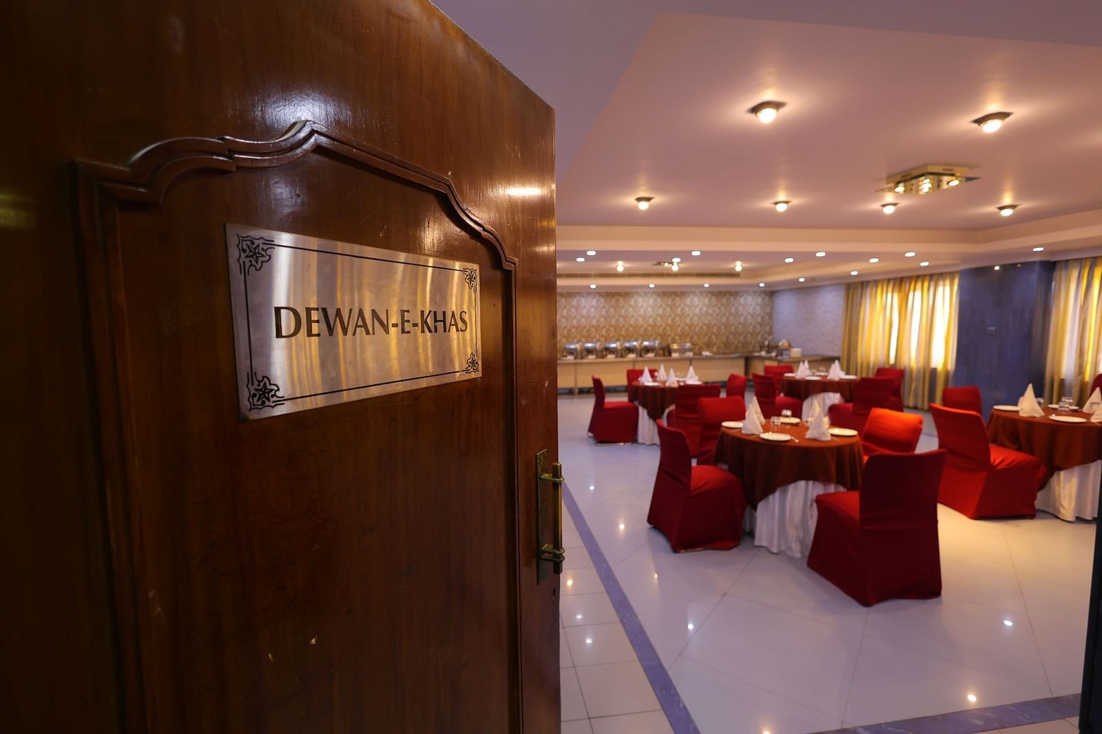 Entrance of Dewaane-e-khas hall of Hotel Amar with red chairs and cluster seating arrangement 