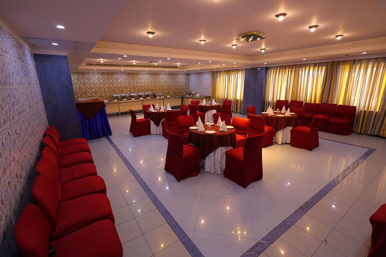Overview image of Dewaane-e-khas hall of Hotel Amar with red chairs and cluster seating arrangement 