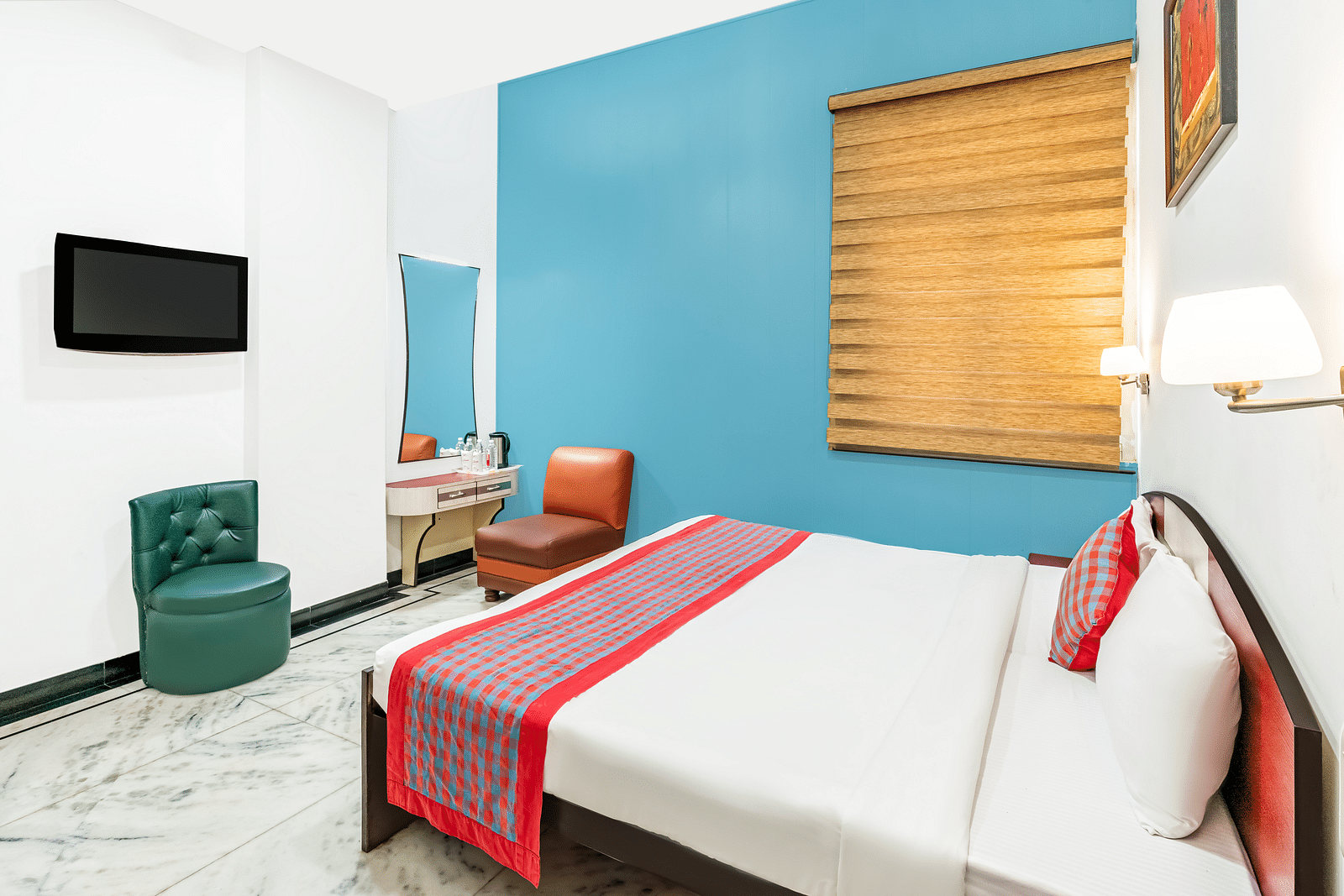 A head-on view of the bedroom at Hotel Moti Palace, featuring a comfy bed, a dressing table, and bedside lighting, creating a welcoming ambiance.