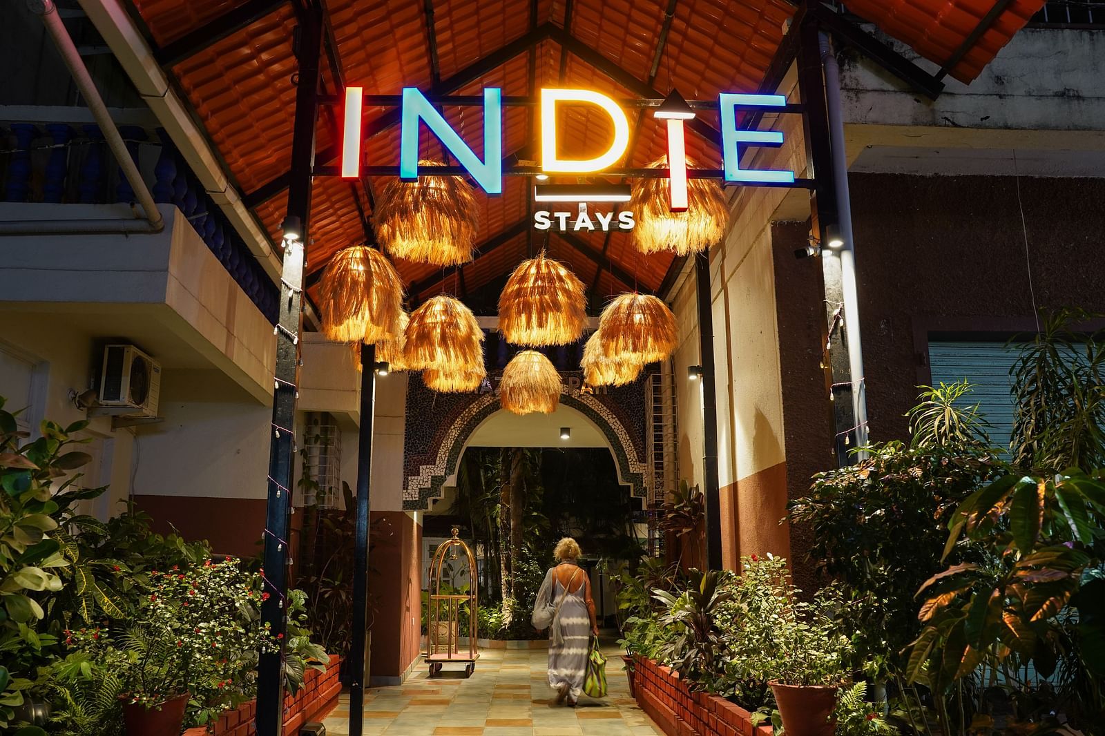 The entrance of Indie Stays features inviting hanging lights and plants on either side, creating a warm and welcoming atmosphere