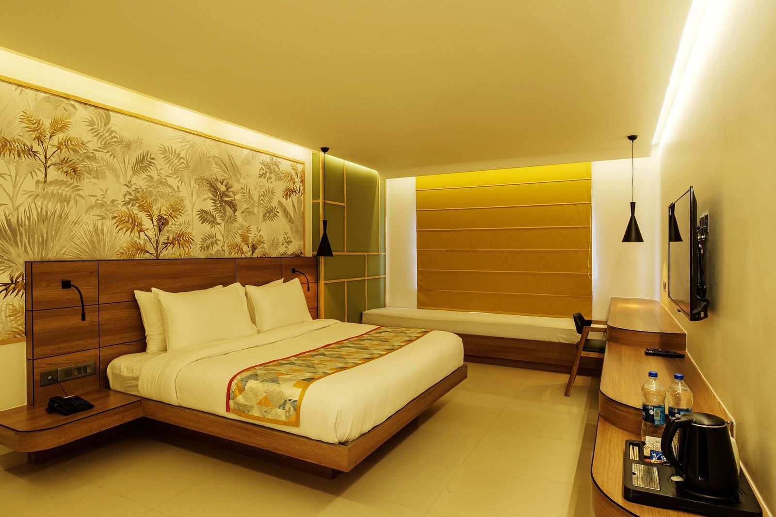 A spacious room with warm lighting, a wooden table opposite with a wall-mounted TV, and cushioned seating by the window for a cosy, relaxing ambience at Indie Stays