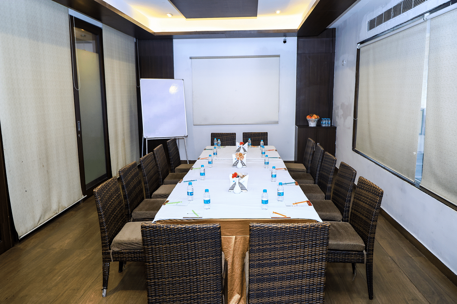 A modern, well-lit meeting room with a long rectangular table, chairs, a whiteboard, and large windows Cotio - The Boardroom at Khanna Fiesta