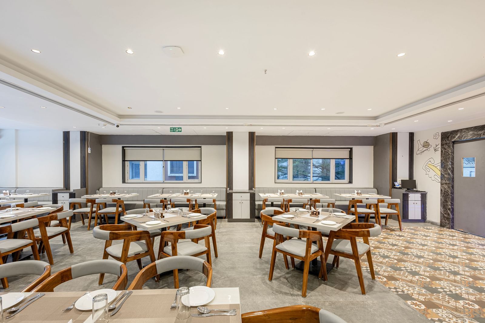 Modern restaurant dining setup with wooden chairs and white tabletops at Lemonridge Hotels, IDPL Balanagar.