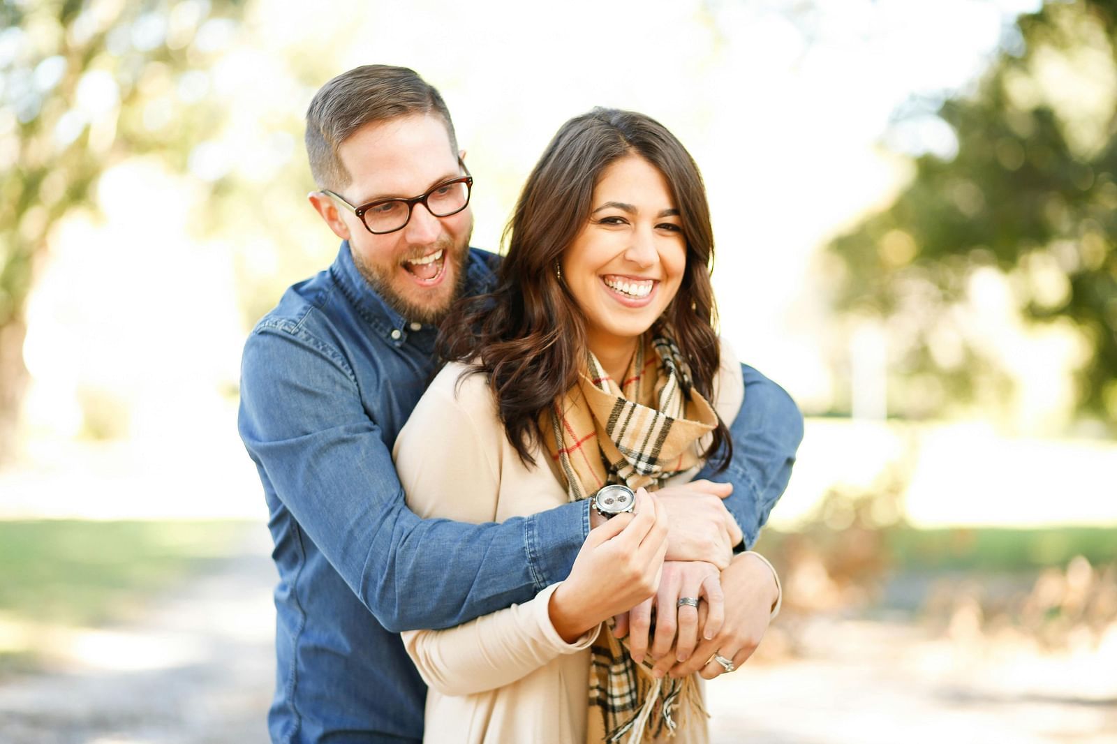 A happy couple holding hands and smiling outdoors, enjoying each other’s company in a natural setting