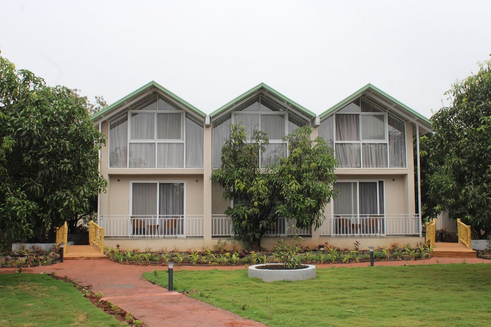 Facade of Mango Leaf Lake Resort, Pune with a garden in front of it