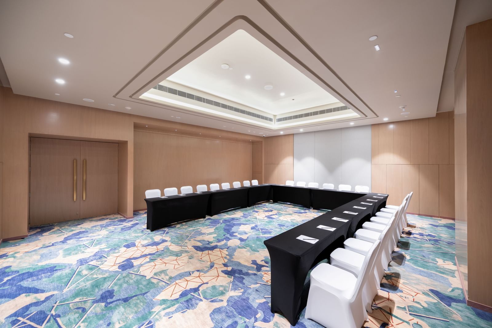 U-shaped boardroom setup at Birch Meeting Room with sleek chairs and patterned carpet at Merlis Hotel, Coimbatore under bright lighting