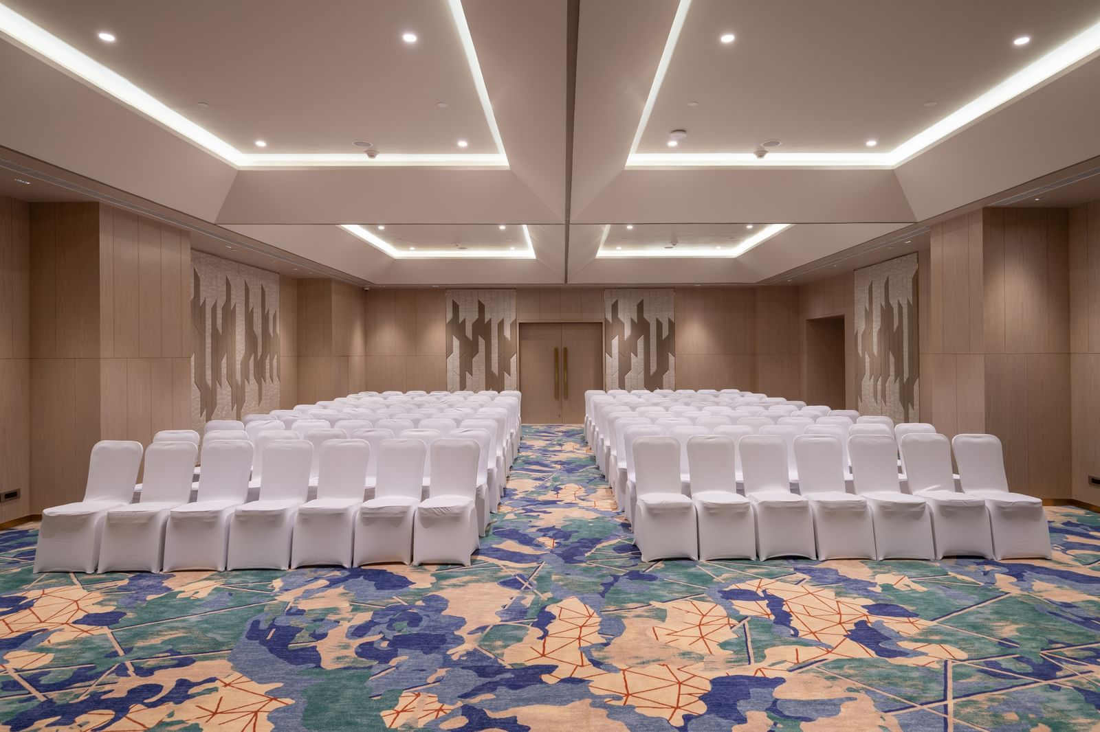 Theatre-style seating in a modern conference hall with patterned carpet at Merlis Hotel, Coimbatore.