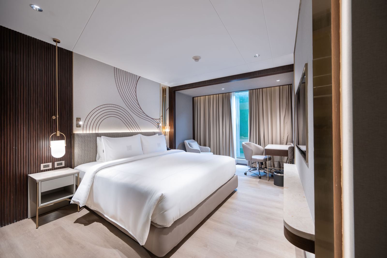 Cosy Premium Suite with a plush bed under warm lighting and a lamp over the nightstand over it at Merlis Hotel, Coimbatore.