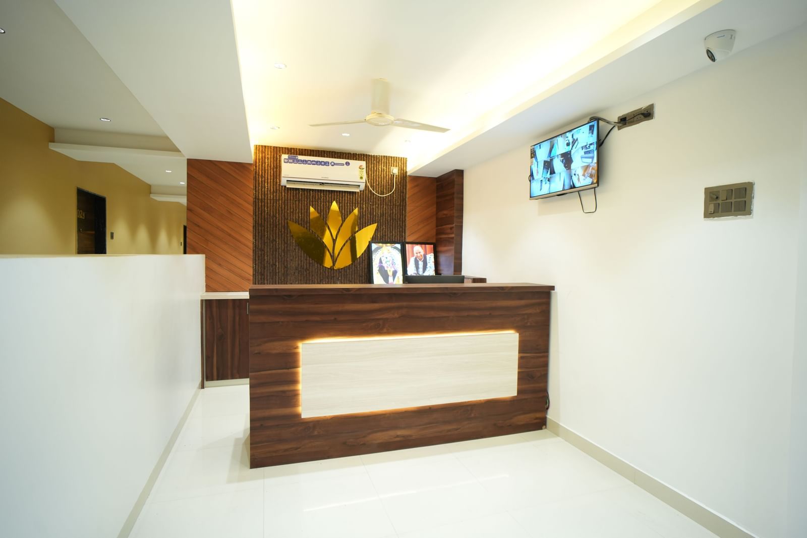 A front desk area at Pravasa Stay Shirdi with a television mounted on the wall and a white ceiling fan overhead.