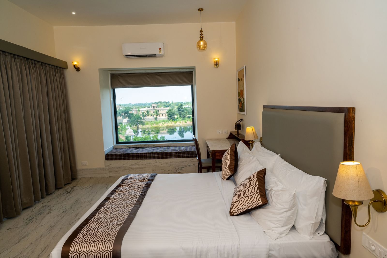 A room with a double bed, night lamps and a window overlooking lush greenery - Rajbagh Wellness, Udaipur