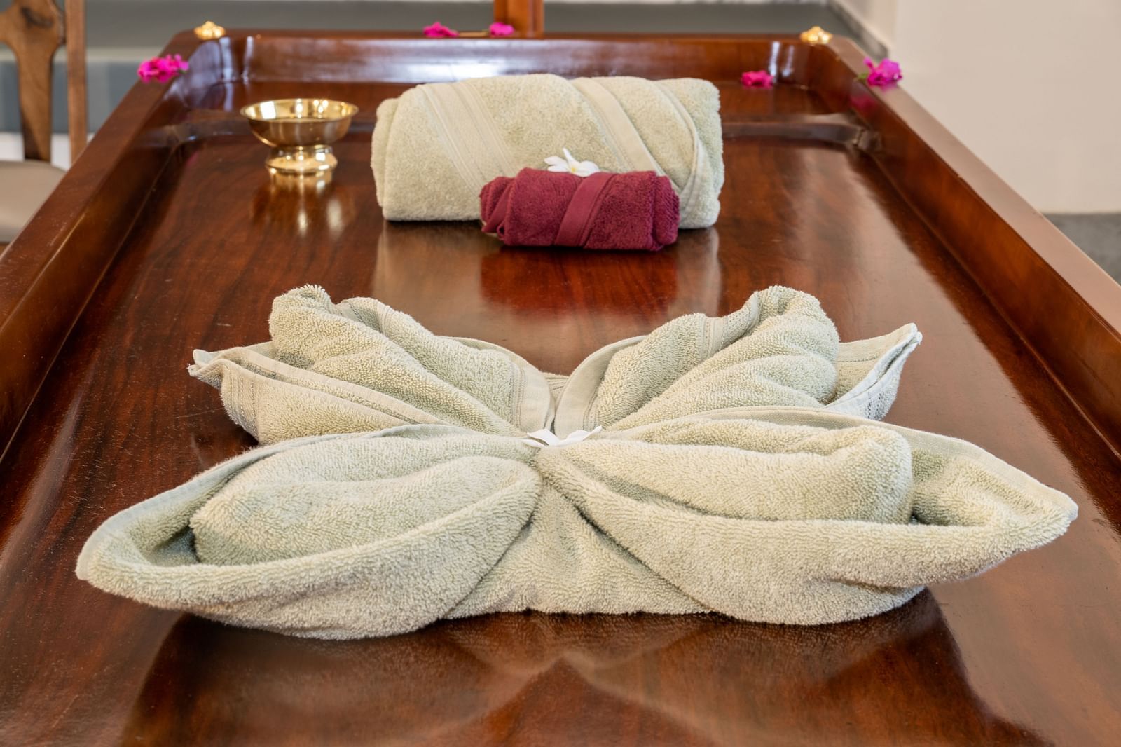 An image of a wooden bed where decorated towels are placed at Rajbagh Wellness