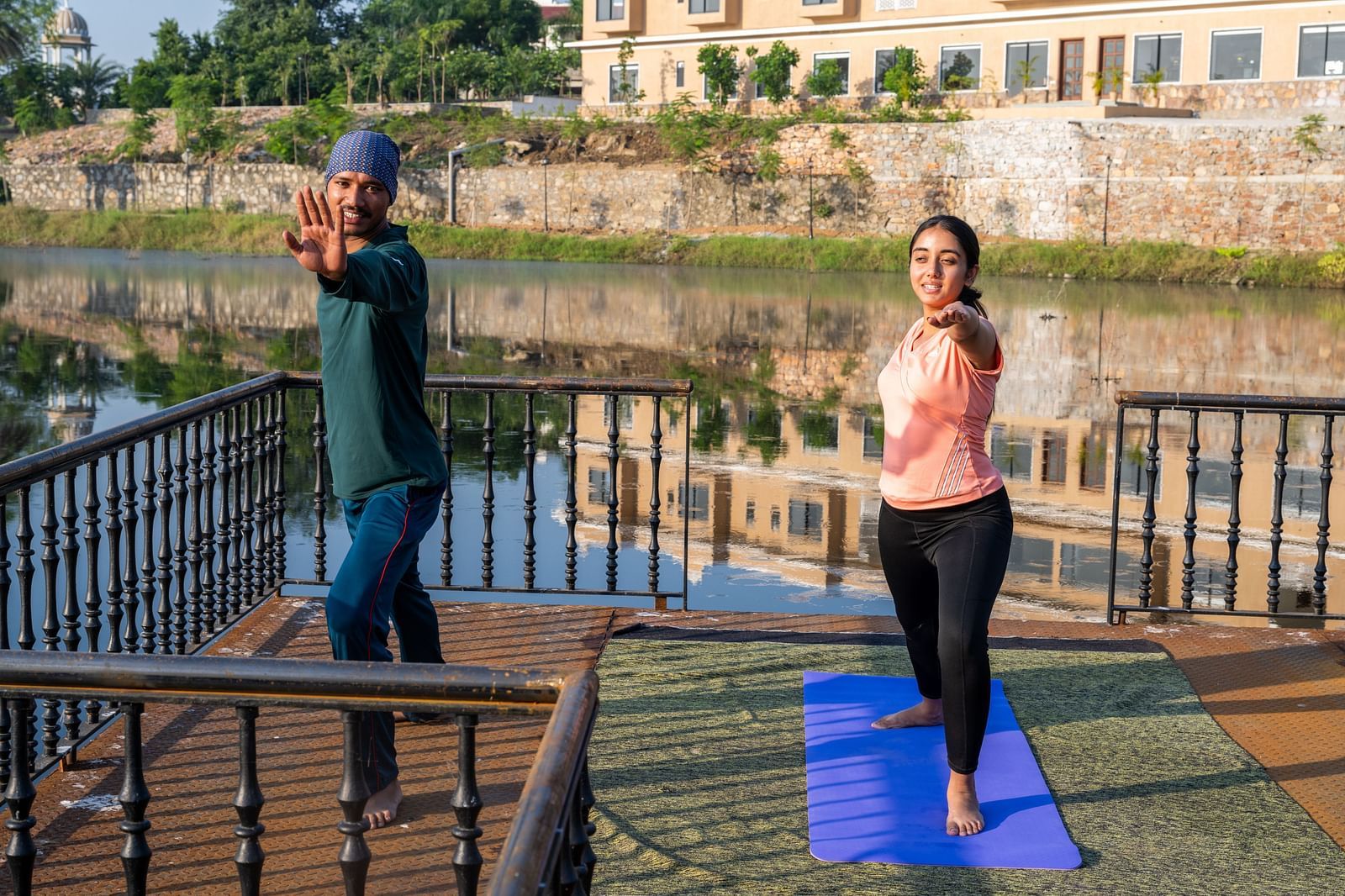 A woman being guided by our yoga instructor during a training session by a water body - Rajbagh Wellness, Udaipur.