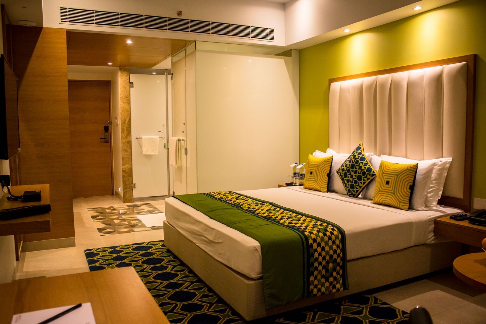 A room with a bed and  pillows arranged on it  along with  a side table | Regency Tirunelveli By GRT Hotels