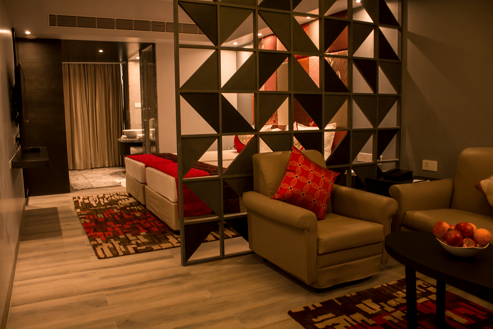 Full view image of sofa and table kept inside a hotel room Image of a room with a bed and  pillows arranged on it  along with  a balcony | Regency Tirunelveli By GRT Hotels