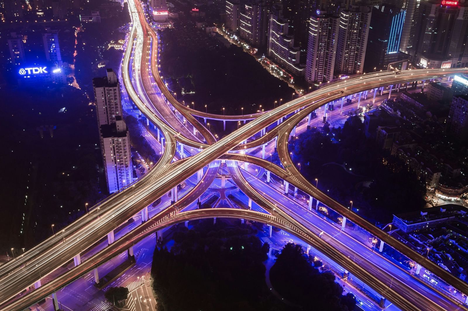 A top view of a flyover with many lanes and vehicles travelling through each one as seen during the night.