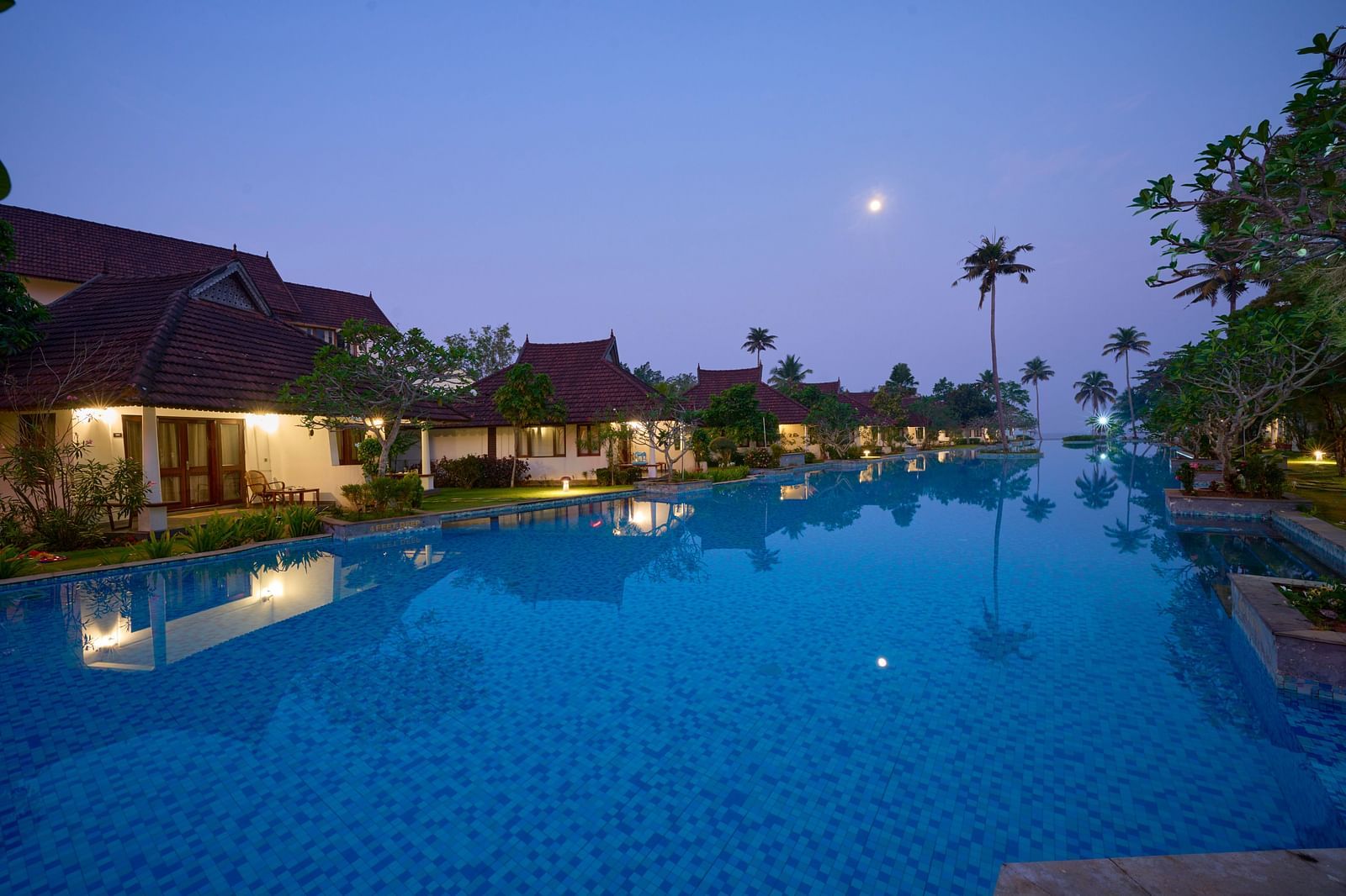 A view of the swimming pool with rooms and trees on the side - Rhythm Kumarakom.