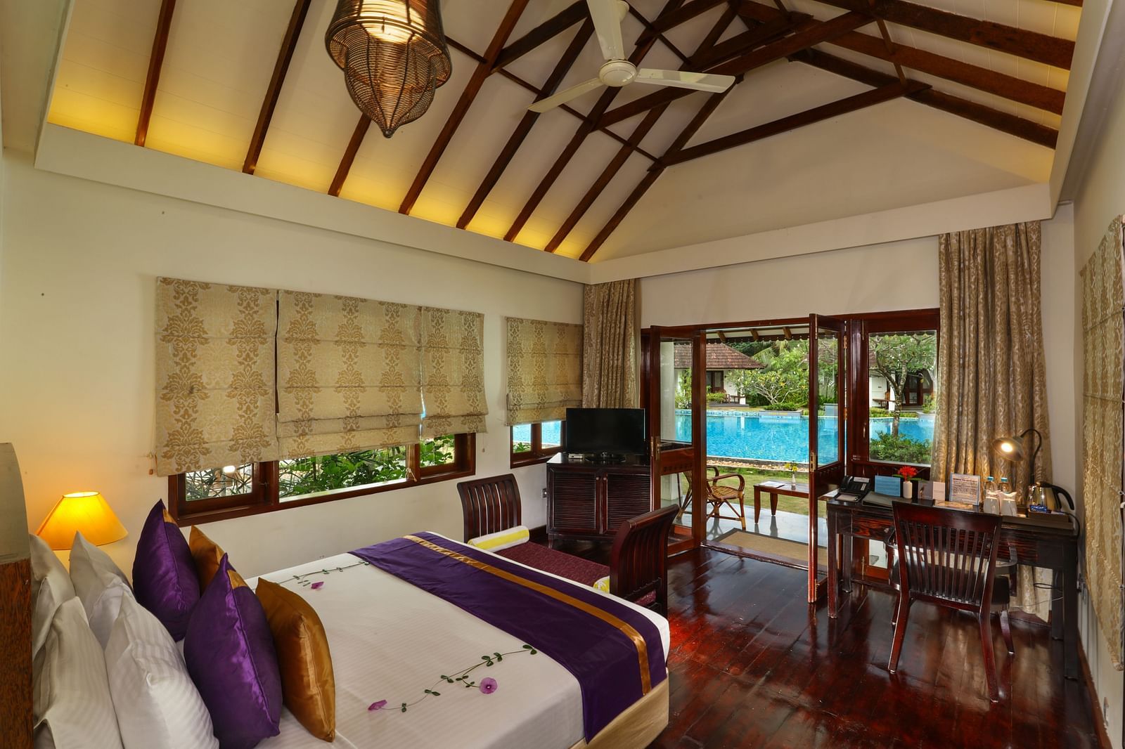 An image of a room with a bed, study desk, a TV  and an outdoor seating area - Rhythm Kumarakom