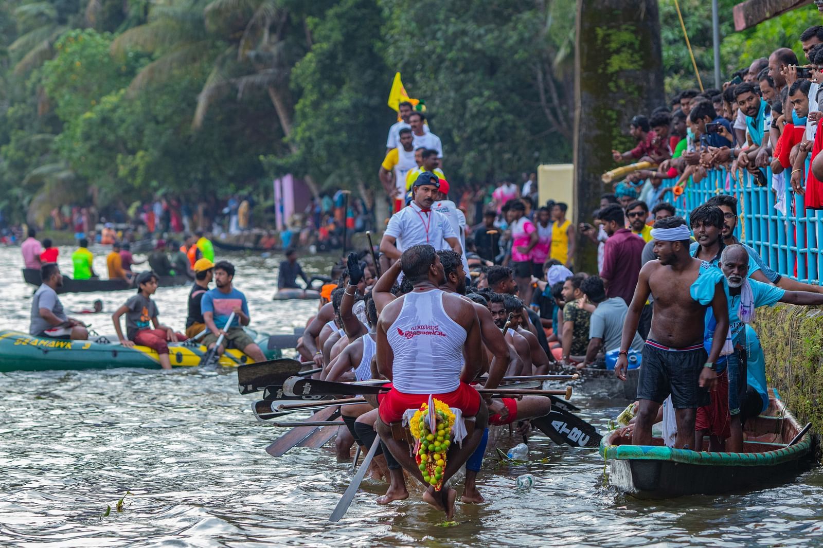A group of boat racers resting after the race with people on the side looking on.