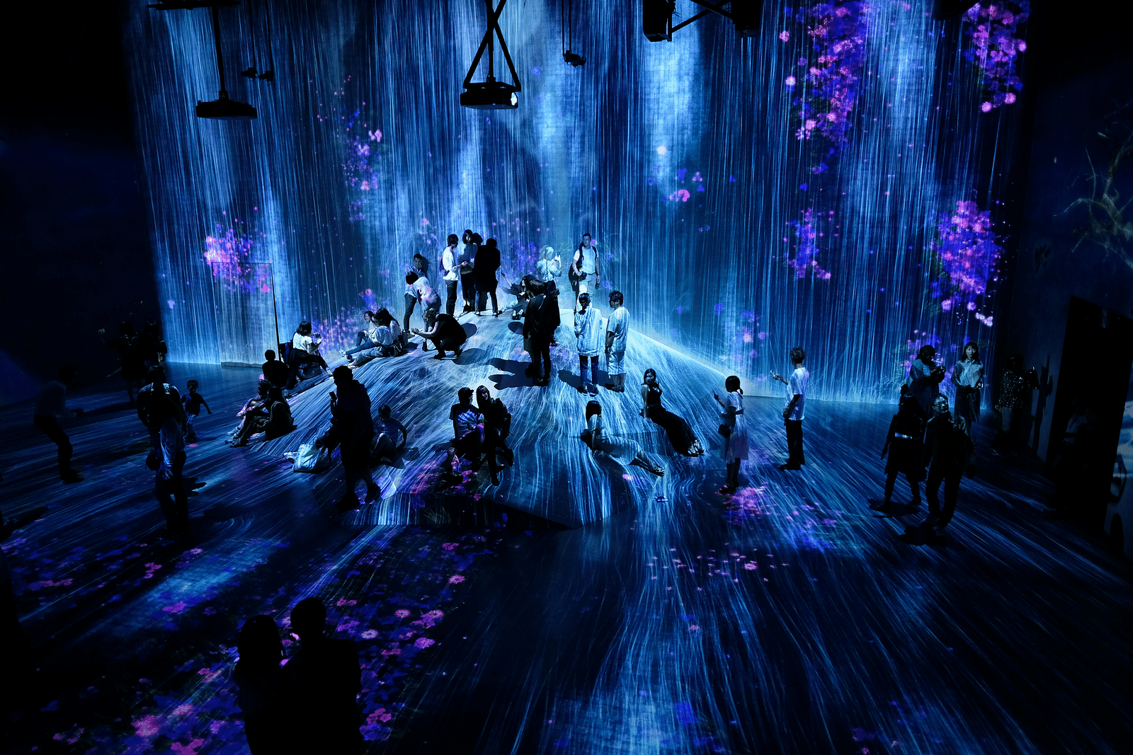 a crowd of people sitting and enjoying a rainfall inside a museum